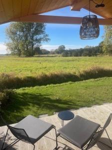 eine Terrasse mit Stühlen und einem Tisch und einem Feld in der Unterkunft Tiny House an der Elbe Bleckede, Niedersachsen in Bleckede
