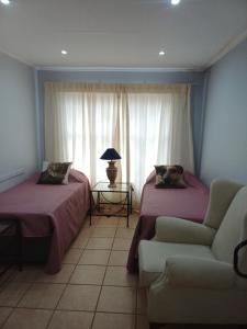 een kamer met 2 bedden, een bank en een lamp bij Bush and Birding Backpacker in Pretoria