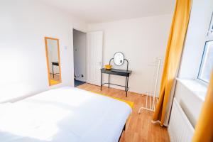 une chambre avec un lit blanc et un miroir dans l'établissement Spacious & High celling 2 Bedroom House, à Cardiff