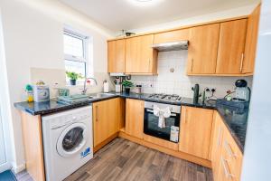 une cuisine avec des armoires en bois et une laveuse et une sécheuse dans l'établissement Spacious & High celling 2 Bedroom House, à Cardiff 19 autres photos