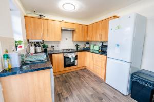 une cuisine avec des armoires en bois et un réfrigérateur blanc dans l'établissement Spacious & High celling 2 Bedroom House, à Cardiff