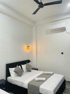 Un dormitorio con dos camas y un ventilador de techo. en Sinharaja Eliphinity Hotel and Restaurant, en Nikawatawana