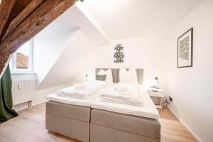 a white bedroom with a large bed and a desk at LudwigsCozyEscape - Historisches Altstadt-Apartment mit Sichtbalken am Residenzschloss, 6 Gäste, SmartTV in jedem Zimmer, Highspeed WLAN, Workspace, 24h Self Check-in, Parkhaus 2 Min Gehweite in Ludwigsburg
