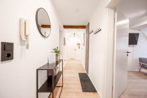a hallway with white walls and a mirror on the wall at LudwigsCozyEscape - Historisches Altstadt-Apartment mit Sichtbalken am Residenzschloss, 6 Gäste, SmartTV in jedem Zimmer, Highspeed WLAN, Workspace, 24h Self Check-in, Parkhaus 2 Min Gehweite in Ludwigsburg
