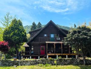 KatoログハウスSprout的一座木屋，红色大门，石墙