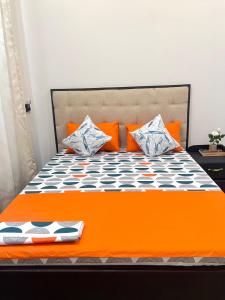 an orange bed with orange and white pillows on it at Ynna Stays in Dar es Salaam +8 photos