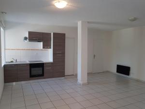 una cucina vuota con mobili marroni e un pavimento piastrellato bianco di L'écrin de l'abreuvoir a Marnay