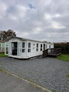 a white mobile home on a gravel lot at Seven Bays Hideaway in Saint Merryn