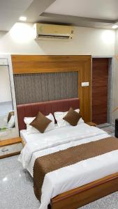 una habitación con una cama grande con sábanas y almohadas blancas en JD Bro Inn, en Sheoganj