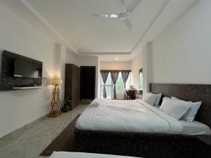 HatikhuliSneha Bhawan Kaziranga的一间带大床和电视的卧室