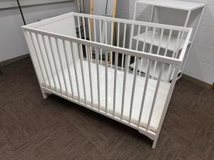 a white crib in a room with a table at Mori Sapporo in Sapporo