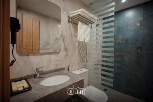 een badkamer met een wastafel, een toilet en een spiegel bij Quaint Hotel Erbil in Erbil +24 foto's