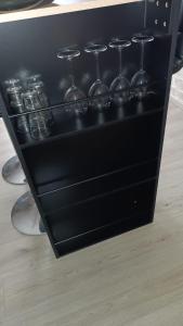 Ein schwarzes Regal mit Weingläsern auf einer Theke in der Unterkunft Le refuge d'Amma in Sessenheim