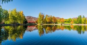 ein See mit Bäumen und ein Gebäude im Hintergrund in der Unterkunft Mogosa Village in Baia Sprie