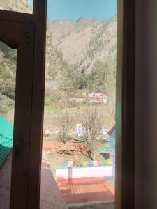 una finestra aperta con vista sulle montagne di Mayaloka cafe & stays a Kasol