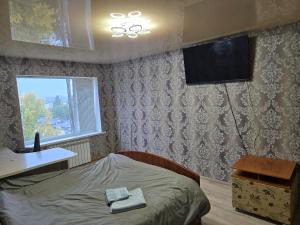 Un dormitorio con una cama y un televisor en la pared. en Квартира-Студія, en Sumy