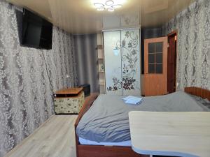 Un dormitorio con una cama, una mesa y un televisor. en Квартира-Студія, en Sumy