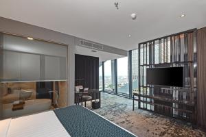 a bedroom with a bed and a tv and a bathroom at JHL Solitaire Gading Serpong in Serpong
