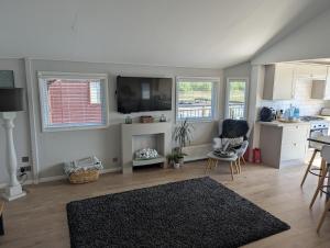 un salon avec une télévision, une table et des chaises dans l'établissement The Boathouse Lodge, à Whelford