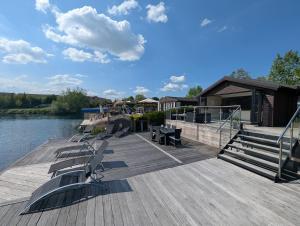 un quai avec des bancs et une maison sur l'eau dans l'établissement The Boathouse Lodge, à Whelford