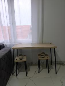 a desk in front of a window with two stools at Chill apartmani Svilajnac in Svilajnac +4 photos