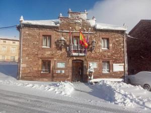 a brick building with two flags in the snow at Casa Rural en BRAÑOSERA in Brañosera