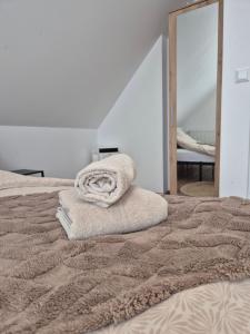 a pile of towels sitting on top of a bed at Domek Noclegowy JoWish in Strachocina