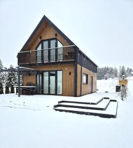 a house in the snow with a deck at Domek Noclegowy JoWish in Strachocina