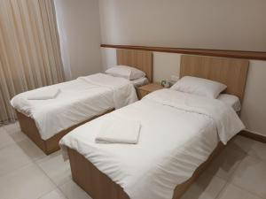 Dos camas en una habitación de hotel con sábanas blancas. en aran hotel, en Duhok