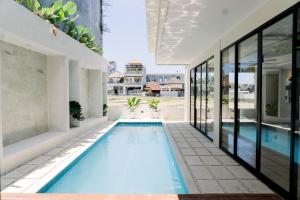 einen Innenpool in einem Haus mit Glastüren in der Unterkunft Stylish Canggu Villa 4BR with Ricefield View in Mantaak