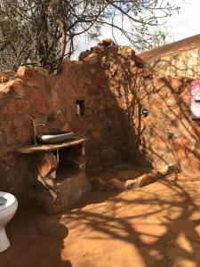 a stone bathroom with a sink and a toilet at Private bush camp with pool cottages tents - 2332 in Ilbisil