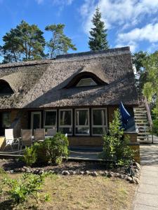 a house with a thatched roof and a porch at FeWo Wald & Düne in Karlshagen