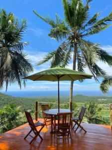 Lajolla Waterfall Resort في Luk: طاولة وكراسي مع مظلة خضراء على السطح