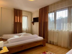 ein Schlafzimmer mit zwei Betten und einem großen Fenster in der Unterkunft Pensiunea Turistică Octavian in Moroeni
