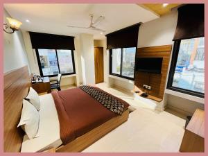 a bedroom with a bed and a tv and windows at Vidyalaxmi Narayan marg Sagar Chandrodaya Varindavan Near Shree Hanuman Tekri Temple and Bankey Bihari Temple - Free Public Parking and Room Service - Fully Air conditioning Luxuary Room - Top Rated Hotel in Vrindāvan