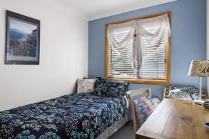 a bedroom with a bed and a table and a window at Jillby's House - 3 BR home near Narrawallee Beach in Narrawallee