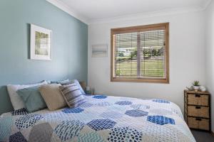 a bedroom with a bed and a window at Jillby's House - 3 BR home near Narrawallee Beach in Narrawallee