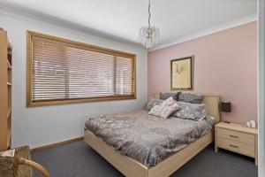 a bedroom with a bed and a window at Jillby's House - 3 BR home near Narrawallee Beach in Narrawallee
