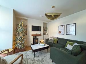 a living room with a green couch and a christmas tree at Hovera Cottage in Windermere