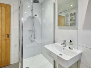 a white bathroom with a sink and a shower at Hovera Cottage in Windermere