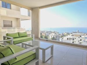 a living room with a couch and a large window at Tabarja Heights in ‘Ayn aş Şughayrah