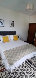 une chambre avec un grand lit blanc avec des oreillers jaunes dans l'établissement ARTIST HOUSE Rooms With View And Shared Kitchen, à Arco da Calheta