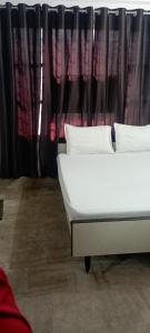 Una cama blanca sentada frente a una cortina. en Sri Raghavendra Inn, en Kākināda