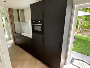 a kitchen with black cabinets and a window at Chalet Aazicht Drenthe met Hottub in Zeyen