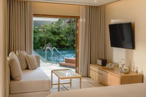 Una sala de estar con un sofá y un televisor en Villa Macaque and Villa Languor, en Railay Beach