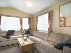 ein Wohnzimmer mit einer Couch und zwei Fenstern in der Unterkunft The Villa At Youlditch Farm in Okehampton