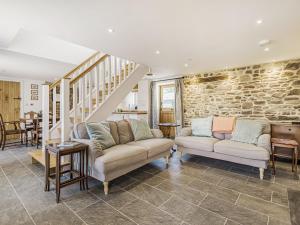 a living room with two couches and a stone wall at The Stables - Cottage in Bryngwyn