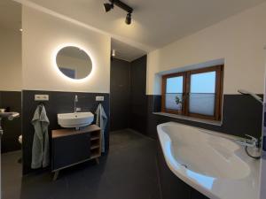 a bathroom with a tub and a sink and a mirror at Ferien im Schwarzwald Dörlinbach II in Schuttertal +34 photos