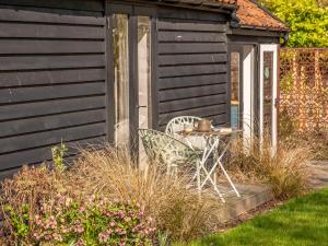 a table and chairs in front of a shed at The Cowshed - Uk50803 in Cratfield