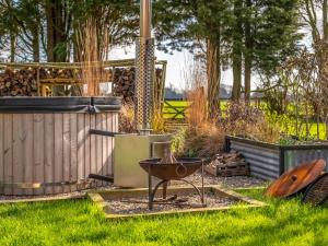 a barbecue in a garden with a fence and trees at The Cowshed - Uk50803 in Cratfield